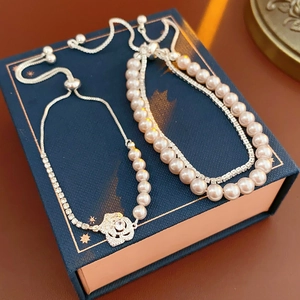 Détail de bracelets en perles avec pendentif rose en zircon sur un coffret bleu