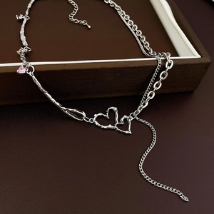 Detailansicht der silbernen Herzkette mit rosa Edelsteinen und Quasten auf Lederhintergrund