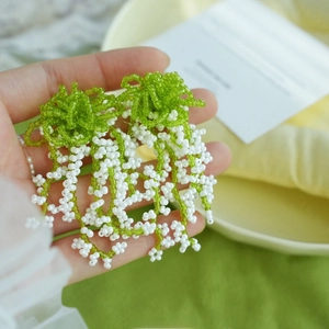 Détail de boucles d'oreilles muguet fait main avec glands aux tons vert et blanc