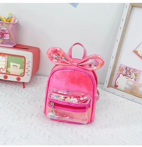 Detailed view of pink bow backpack with transparent sequin front pocket and glitter effect