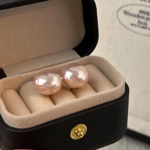 Macro detail of high-luster pink pearl earrings in a black textured jewelry box