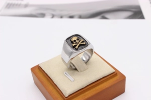 Macro detail of men's skull and crossbones signet ring with gold-tone relief and black finish