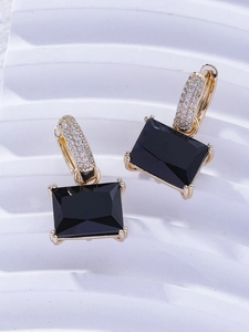 Detail of gold huggie earrings featuring micro-pave white crystals and black emerald-cut stones