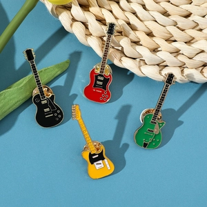 Set of four colorful guitar enamel pins in black red green and yellow on blue background