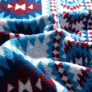 Close-up of thick ethnic knit shawl featuring blue and red geometric pattern texture