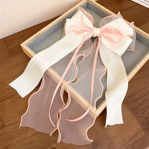 Detailed close-up of layers of cream and pink lace ribbon bow on a gray velvet display tray