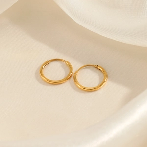 Minimalist gold-plated stainless steel hoop earrings on soft white silk background
