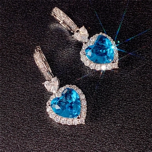 Detail of silver heart earrings with blue topaz zirconia and sparkling stone halo
