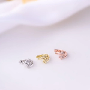 Macro shot of three geometric pavé zircon huggie earrings in silver, gold, and rose gold