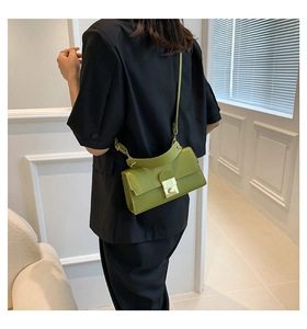 Πράσινη τσάντα χιαστί με χρυσό κούμπωμα και λαβή, φορεμένη πάνω σε μαύρο σακάκι
