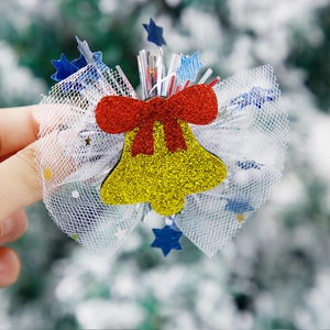 Detail of Christmas hair clip with yellow bell, red bow, and blue stars on white mesh