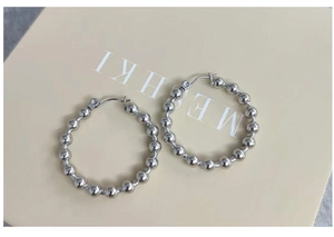 Vue détaillée des boucles d'oreilles créoles perlées argentées avec une finition métallique