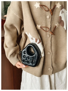 Detailed view of a black jelly bag with a gold chain strap worn by a female model