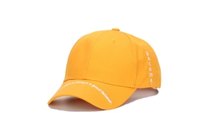 Detailed close-up of yellow cotton baseball cap with white embroidered text on the brim