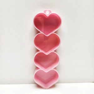 Close-up of pink heart-shaped 4-compartment plastic storage box for small jewelry beads