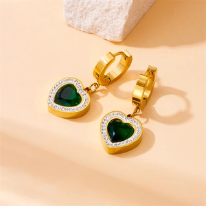 Golden heart earrings with green emerald stone and diamond halo on stone background