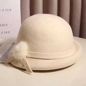 Detail of elegant wool beret featuring a satin band and soft fur pompom decoration