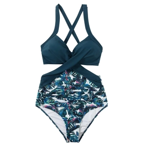 Detail of tropical print monokini with dark green crossover straps and cutout waist