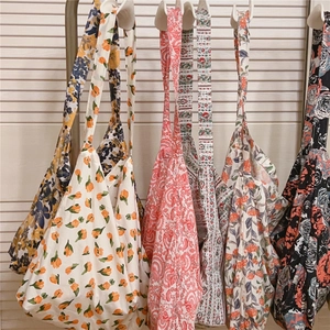 Sacs cabas en toile de coton aux imprimés floraux variés sur un fond de mur neutre