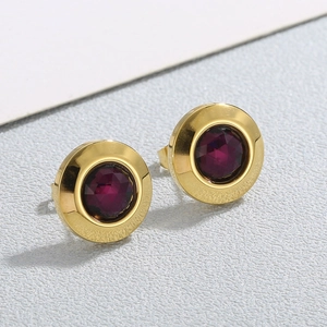 Detail view of round gold-plated stud earrings with faceted deep purple crystal stones