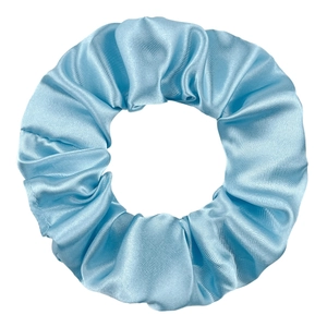 Macro detail of sky blue satin scrunchie showing glossy texture and elastic fabric pleats