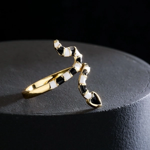 Bohemian 18K gold plated snake ring with black and white enamel on a dark textured surface