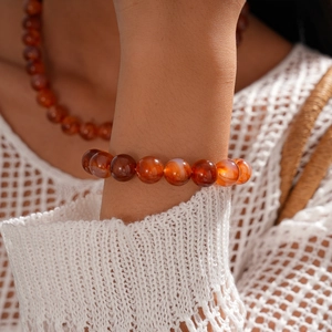 Detail of red agate beaded bracelet on wrist with translucent geometric texture