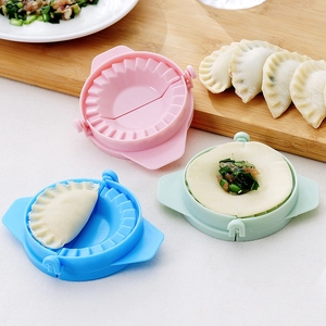 Tres moldes para empanadillas de plástico en rosa, azul y verde sobre tabla madera