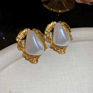 Gros plan de boucles d'oreilles perle vintage avec texture martelée dorée irrégulière