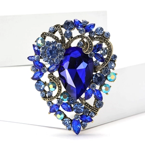 Detail of vintage heart brooch with deep blue crystal and rhinestones on gold alloy