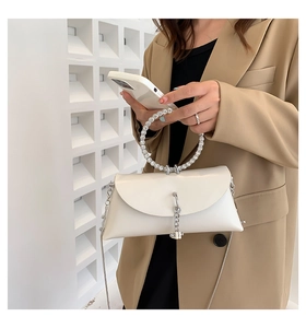 Detail of white crossbody bag with rhinestone handle and silver chain strap