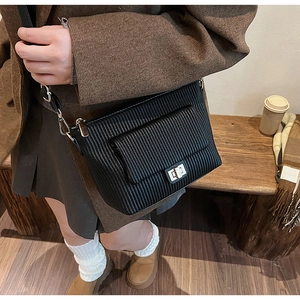 Détail du sac bandoulière plissé noir avec fermoir rotatif argenté et texture sangle