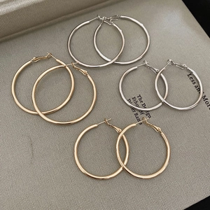 Detailed view of silver and gold geometric hoop earrings in various sizes on a book