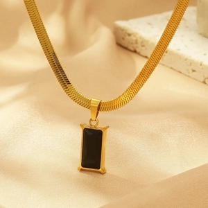 Dettaglio della catena a serpente dorata con un pendente rettangolare nero minimalista
