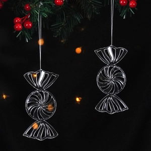 Detail of transparent candy-shaped Christmas ornaments with warm bokeh lights background