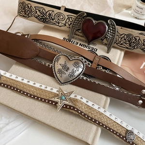 Detail of vintage leather belts with heart wings buckle and turquoise stars on canvas