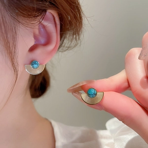 Macro view of vintage gold fan-shaped earring with textured turquoise inlay detail