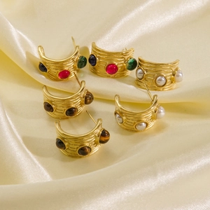 Detailed close-up of C-shaped 14K gold earrings with pearls and natural stone insets