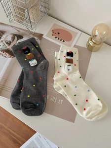 Dettaglio di calze a pois grigie e bianco sporco con teste di animali in peluche 3D
