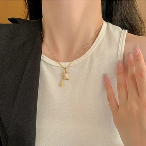 Detail of gold necklace featuring moon and star pendants with zirconia on female model