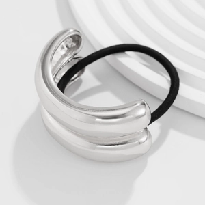Close-up of a glossy silver metallic curved hair ring with a black elastic band detail