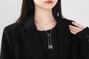 Silver infinity pendant necklace on model wearing a black blazer with Y-shaped chain detail