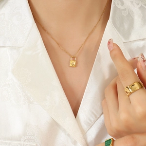 Gold lock pendant necklace with sun motif and zircon stones worn by a model