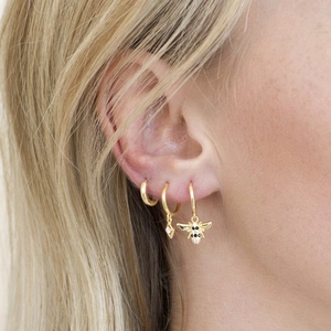 Close-up of gold s925 silver hoop earrings with bee and geometric pendants on model