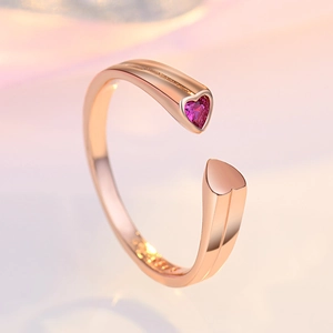 Macro detail of rose gold open ring featuring a vibrant pink heart-shaped crystal stone