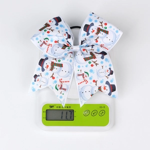 Close-up of a Christmas snowman bow hair tie weighing 11.7g on a digital kitchen scale