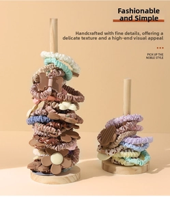 Vertical wooden stand displaying assorted hair scrunchies and ties in earthy tones