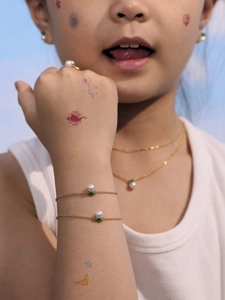 Detail of children's crown pearl jewelry set featuring a gold necklace and bracelet