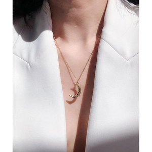 Elegant gold crescent moon pendant necklace for women on a model with white suit