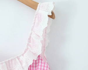 Detailed close-up of pink plaid top with white lace trim and floral embroidery